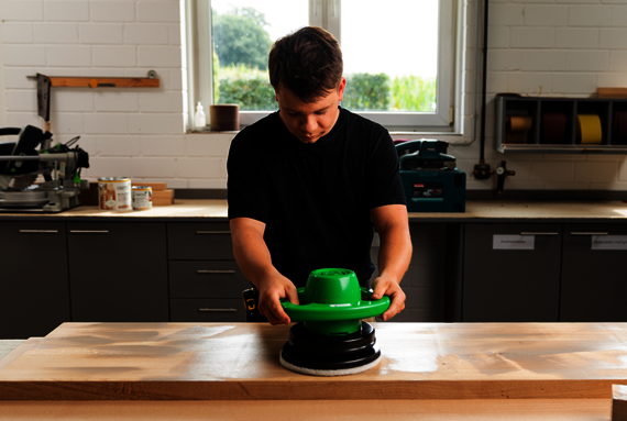 L'artisan masse l'Huile pour Bois 2K Osmo dans la surface du bois à l'aide du HandXcenter