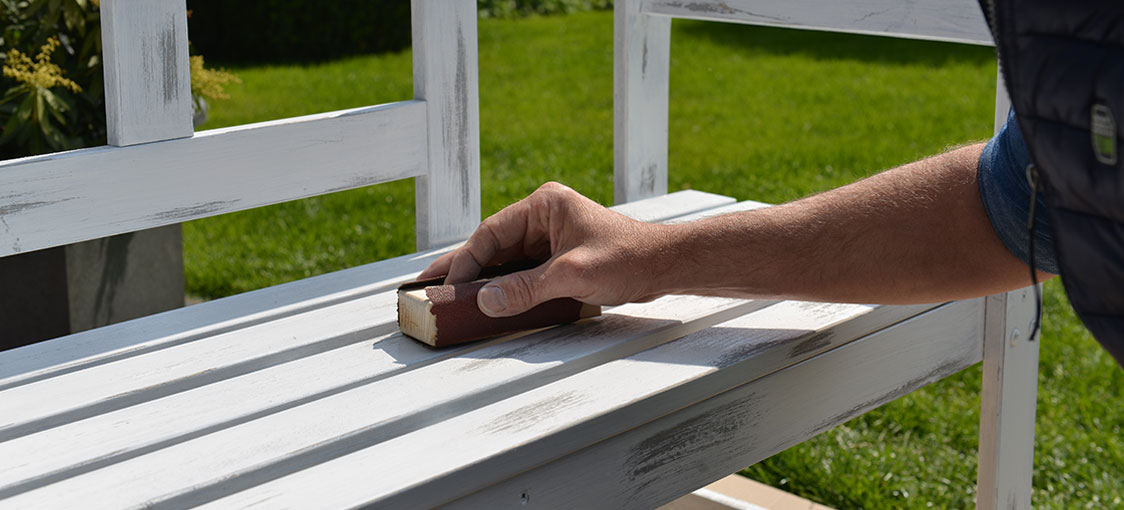Banc vintage Osmo à réaliser soi-même : après le deuxième Séchage de 12 heures, poncez délicatement la deuxième couche de peinture à différents endroits à l'aide d'un papier abrasif fin. Travaillez dans le sens du grain du bois et poncez légèrement les bords.